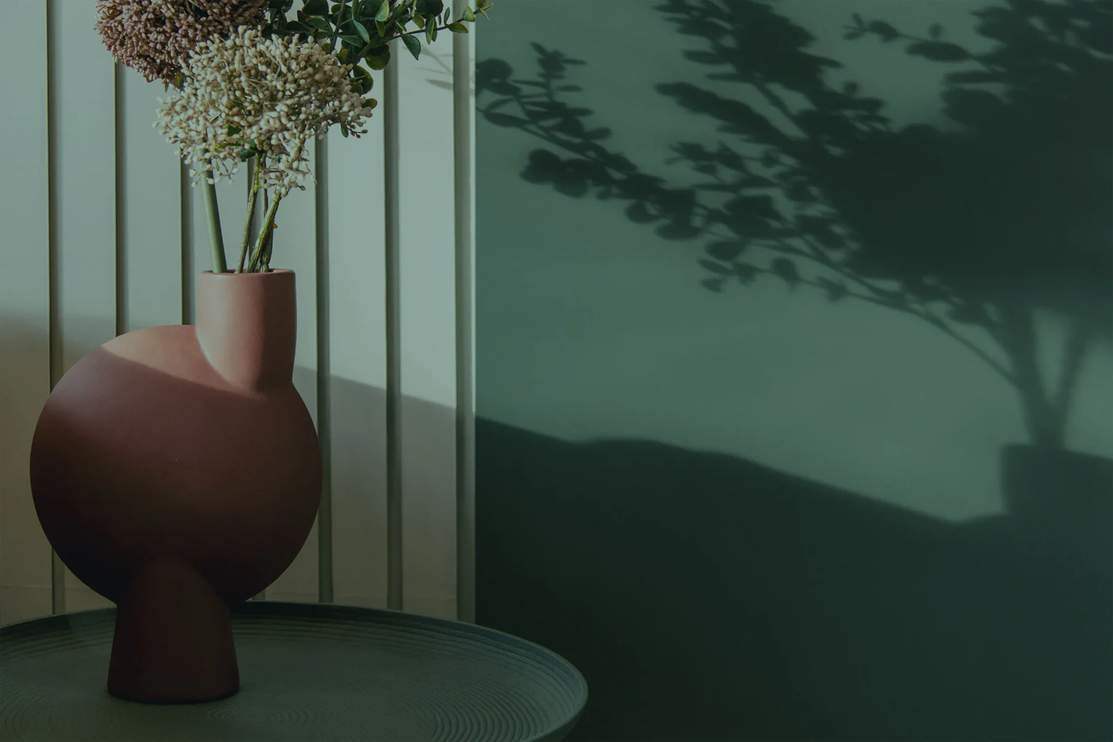 Terrakottavase vor der grünen Wandvertäfelung im Studio The BLISS